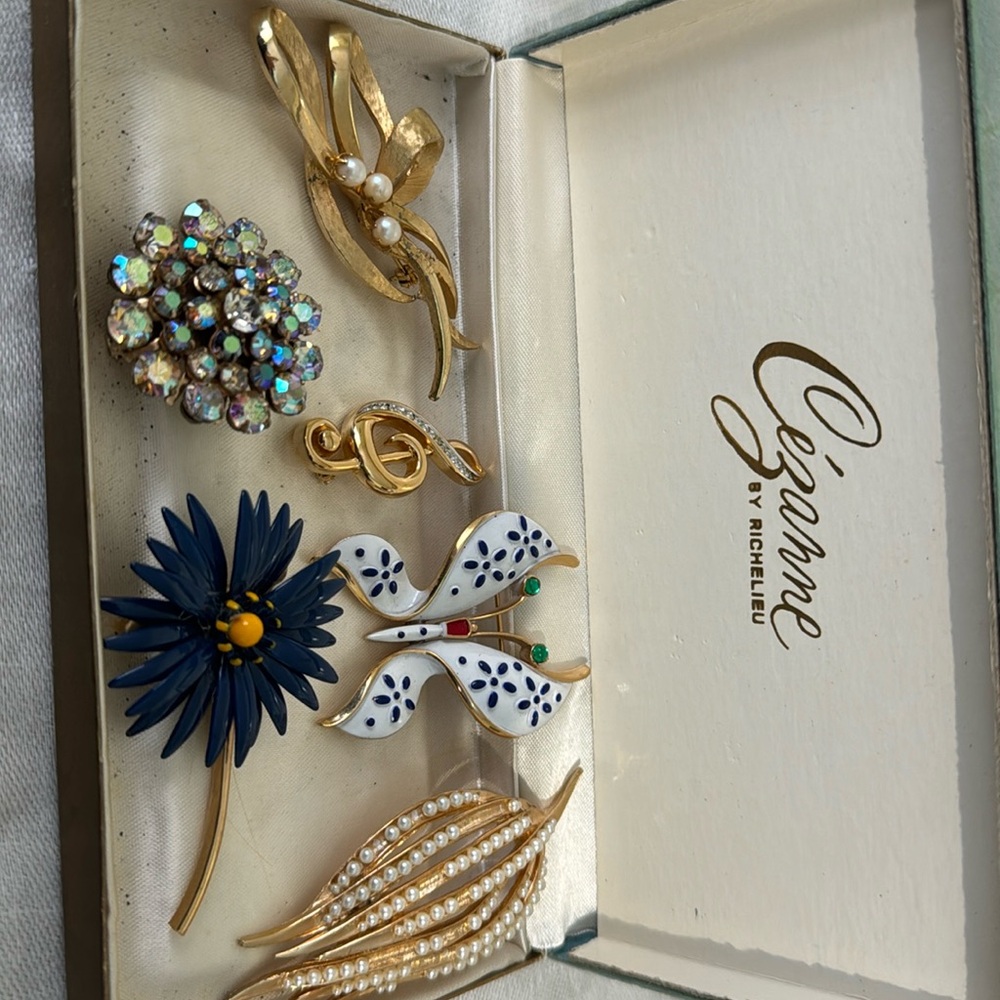 Satin box of seven vintage lapel pins.